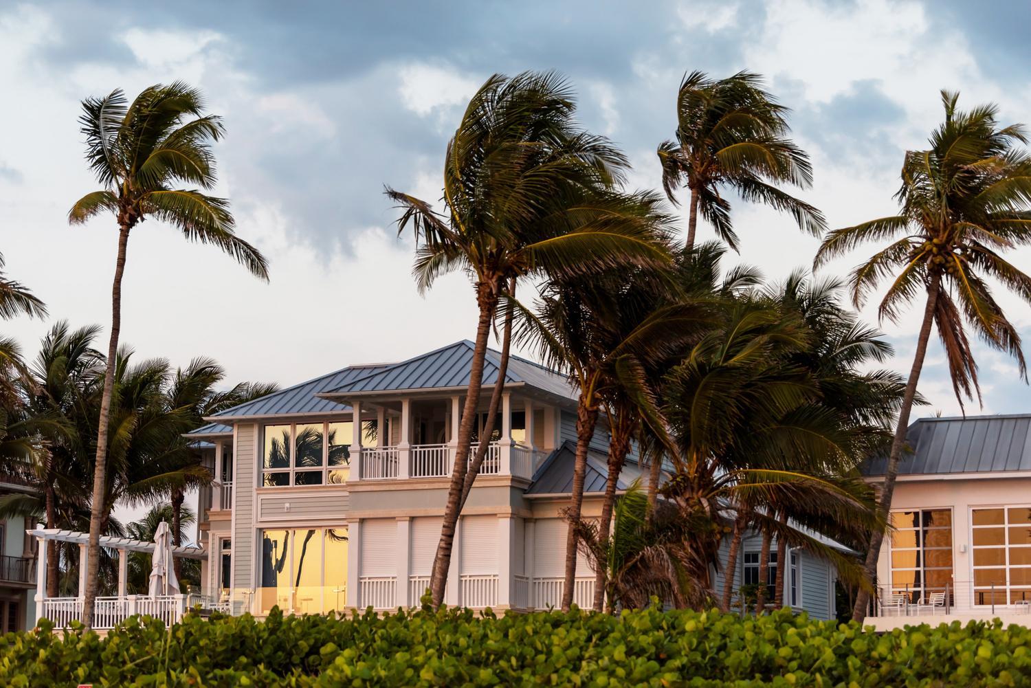 Coast house beachfront waterfront vacation home, house during evening sunset with nobody in Florida, gulf of mexico, storm weather and wind palm trees