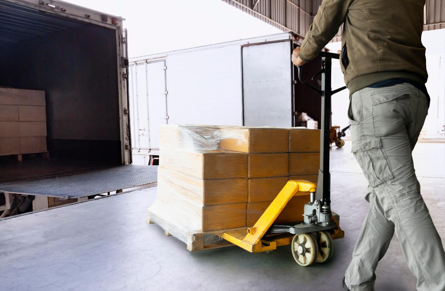 Workers Using Hand Pallet Jack Unloading Package Boxes into Carg